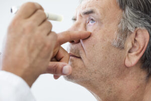 Elderly man being examined by an ophthalmologist, illustrating diagnosis and treatment planning for wet age-related macular degeneration with intravitreal injections